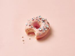 Close-Up Photograph of a Donut with Diamonds on a Pink Surface