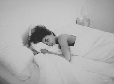 woman lying on bed covered by white blanket